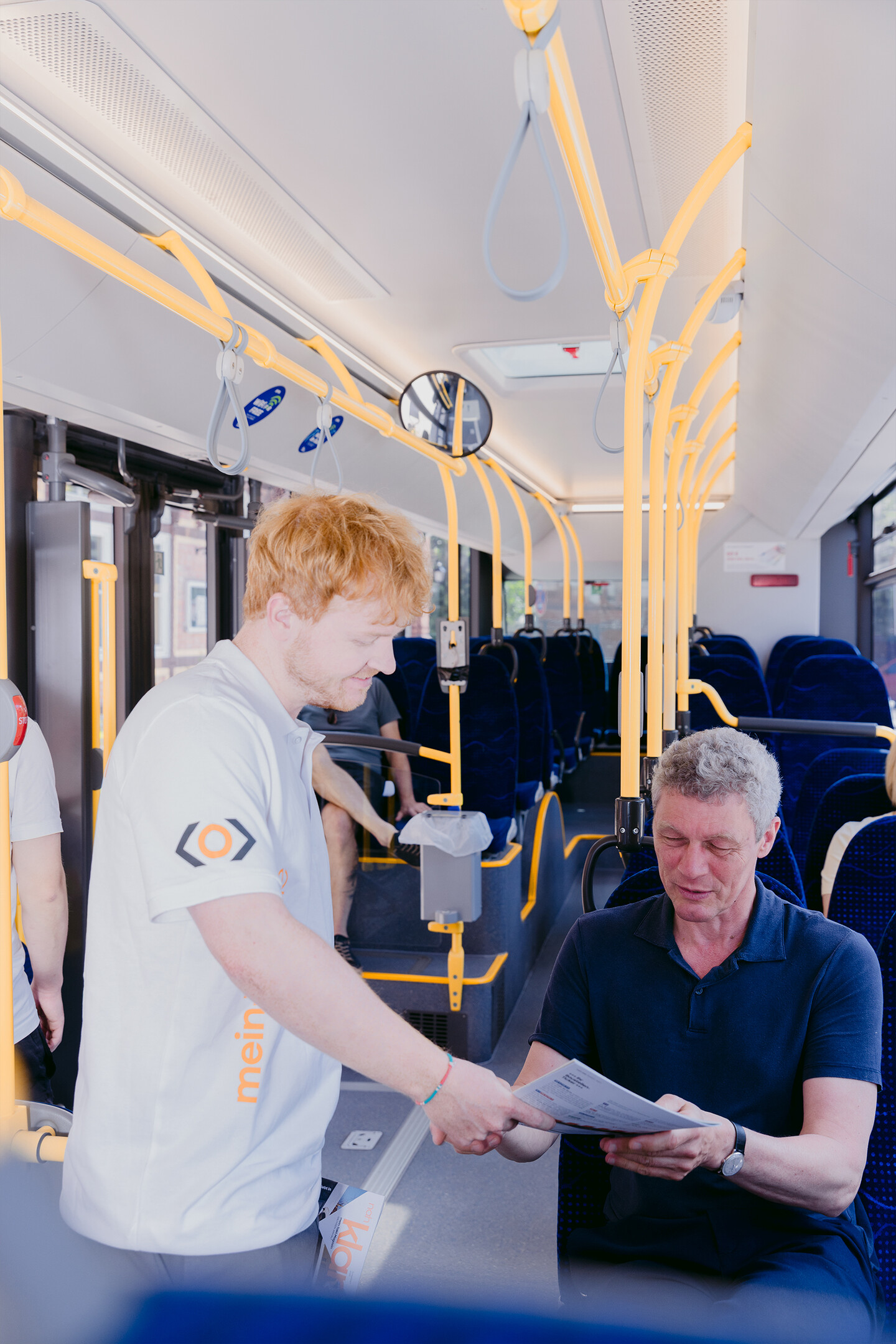 Dominik Glotz zeigt einem Fahrgast im Bus einen Fahrplan