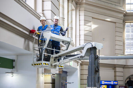 Frischekur in Halle ©Deutsche Bahn AG / SnapArt | Michael Kremer Zwei Männer in Arbeitskleidung und Schutzhelmen stehen auf einer Hebebühne im Bahnhof Hallle. Sie halten Putzwerkzeuge in der Hand